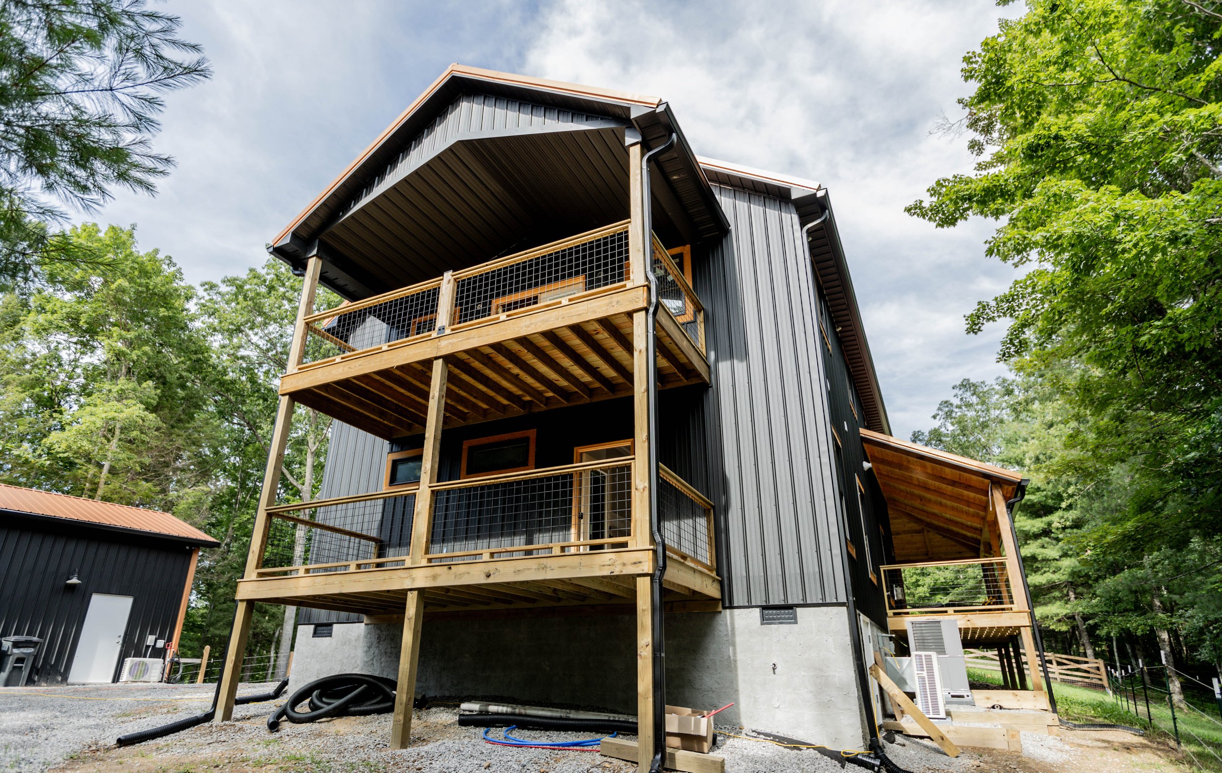 Custom black board-and-batten barndominium with two-story deck
