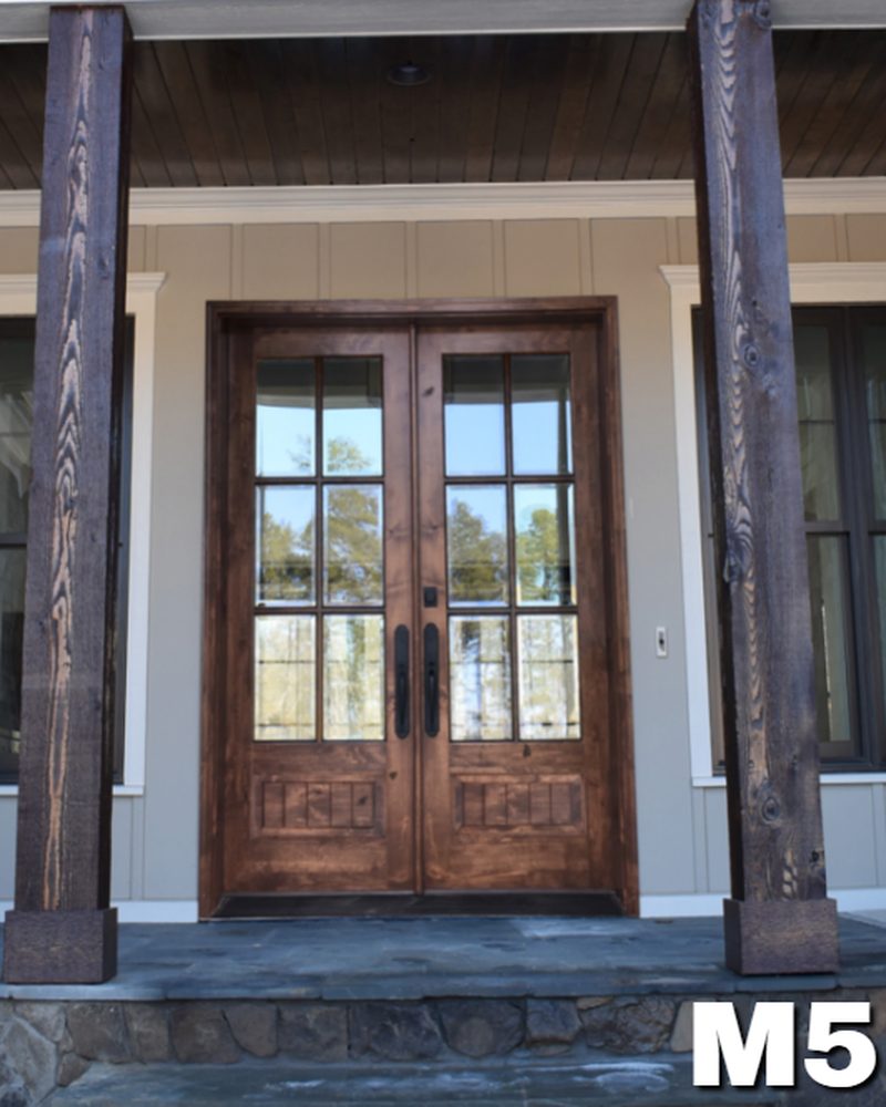 M5 knotty alder double entry door with raised panels, framed by dark timber porch posts